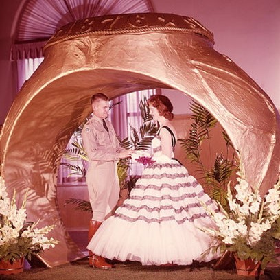 A couple posing in front of a replica of the Aggie Ring during a Ring Dance event from the 1940s.