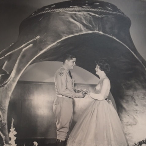 A couple posing in front of a replica of the Aggie Ring during a Ring Dance event from the 1960s.